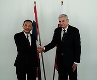 Two men in suits in front of the flags of Poland and Thailand