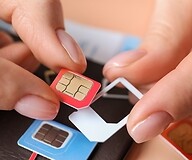 The hand of a person holding a SIM card for replacement in their fingers