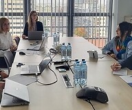 A group of people are sitting at a table in a conference room