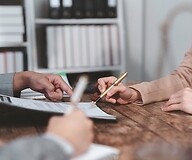 The hands of two people on a document being read
