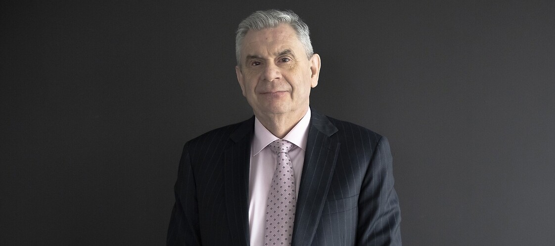 Mężczyzna w jasnej koszuli i ciemnej marynarce na ciemnym tle