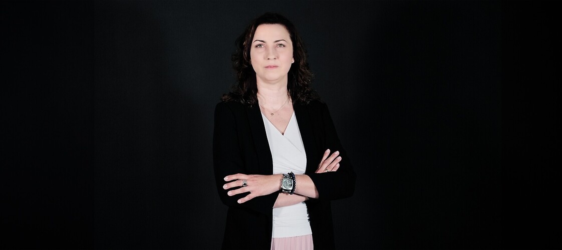 Kobieta w czarnej marynarce i białej koszuli na ciemnym tle