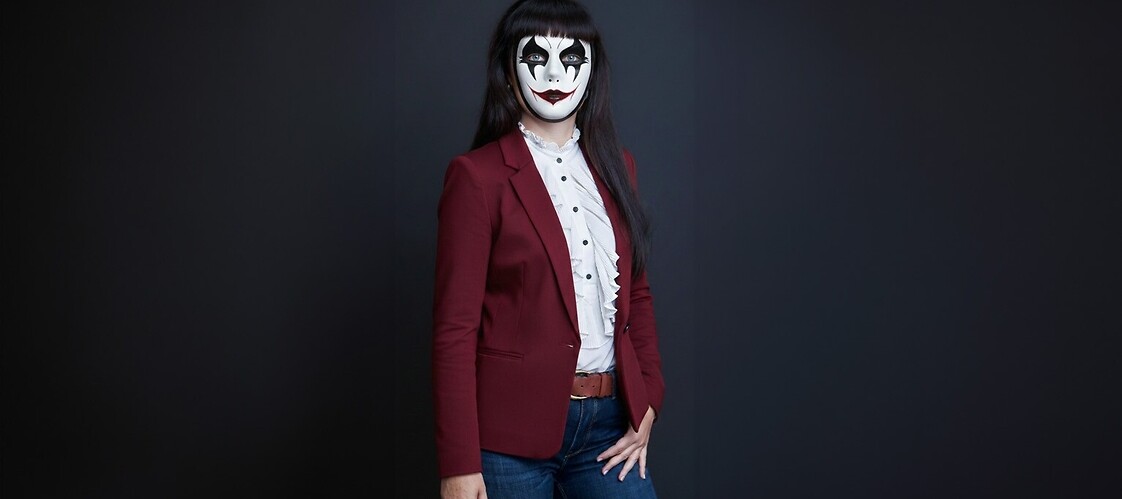 Konieta w żakiecie i spodniach, w masce weneckiej, na ciemnym jednolitym tle