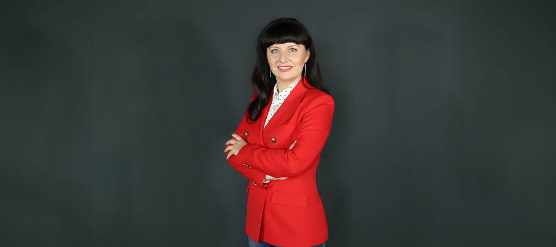 Kobieta w czerwonym żakiecie i białej bluzce na ciemnym jednolitym tle