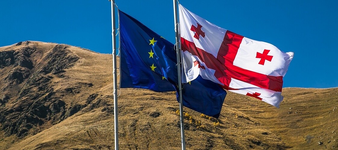 Gruzińska oraz unijna flaga na tle gór.