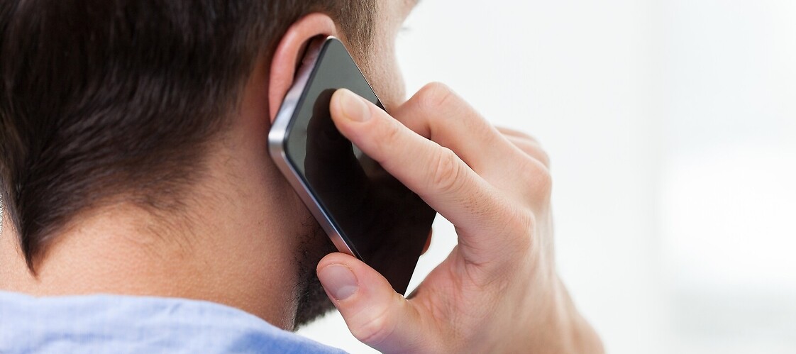 Mężczyzna stojący tyłem trzyma przy uchu telefon komórkowy