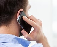 Mężczyzna stojący tyłem trzyma przy uchu telefon komórkowy