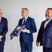 Trzech mężczyzn w garniturach na białym tle, jeden z nich trzyma ...