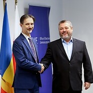 Dwóch mężczyzn pozuje do zdjęcia, za nimi flagi Moładawii i Polski