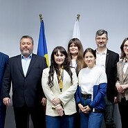 Grupa osób pozuje do zdjęcia, za nimi flagi Mołdawii i Polski oraz rollup z ...