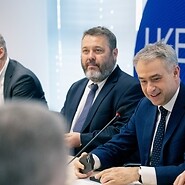 Trzech mężczyzn w garniturach za stołem konferencyjnym