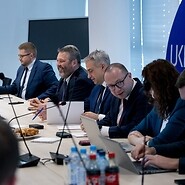 Grupa osób za stołem konferencyjnym, w tle logo UKE