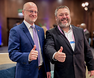 Dwóch uśmiechniętyvh męzczyzn w garniturach w przestrzeni konferencyjnej