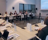 Grupa osób za stołami w sali konferencyjnej