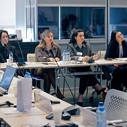 Grupa osób za stołami w sali konferencyjnej