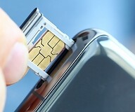 Palce trzymajace kartę sim wkładaną do gniazda w smartfonie