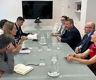 Grupa osób po obu stronach stołu konferencyjnego