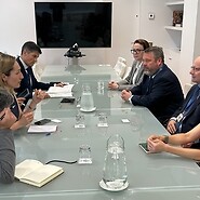 Grupa osób po obu stronach stołu konferencyjnego