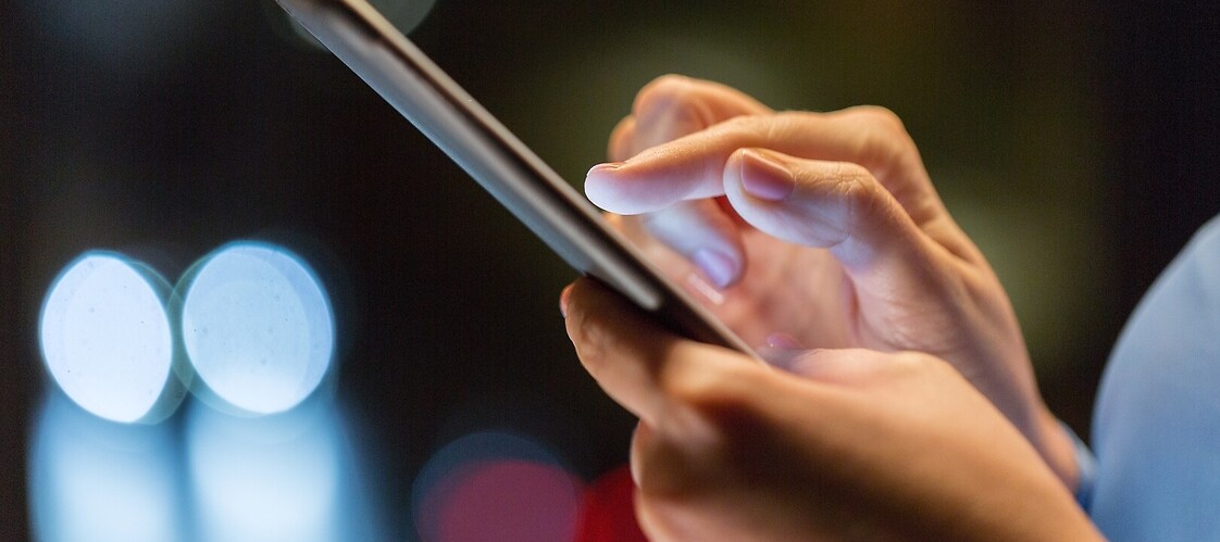 Dłoń osoby wybierającej numer na smartfonie