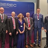 Grupa osób pozuje do zdjęcia na tle ścianki z logotypem BEREC