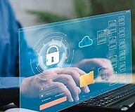 ręce na klawiaturze, na pierwszym planie ikony cyberbezpieczeństwa