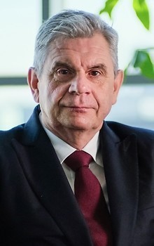 Prezes Jacek Oko w ciemnym garniturze i bordowym krawacie